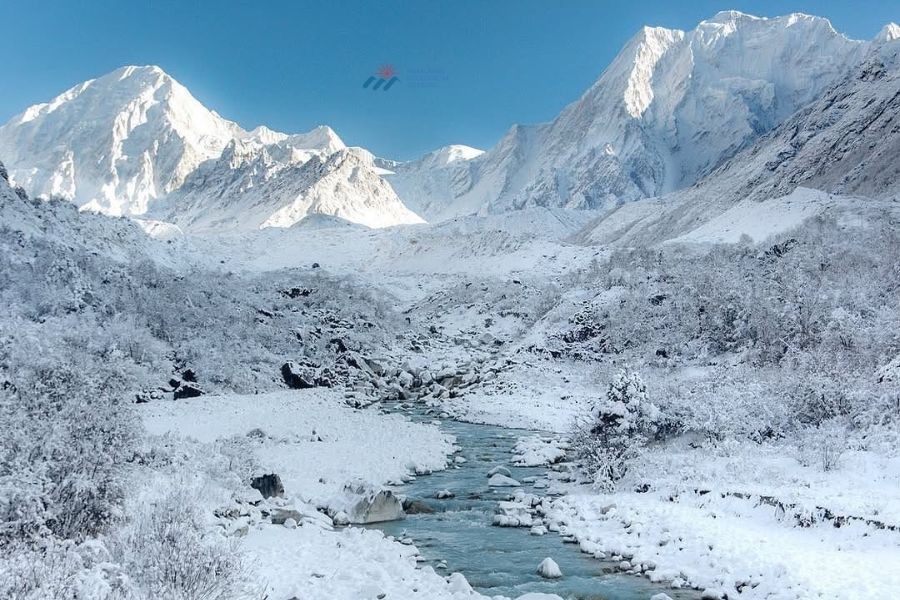 Snow-covered Himalayan peaks with a turquoise river flowing through a white winter valley